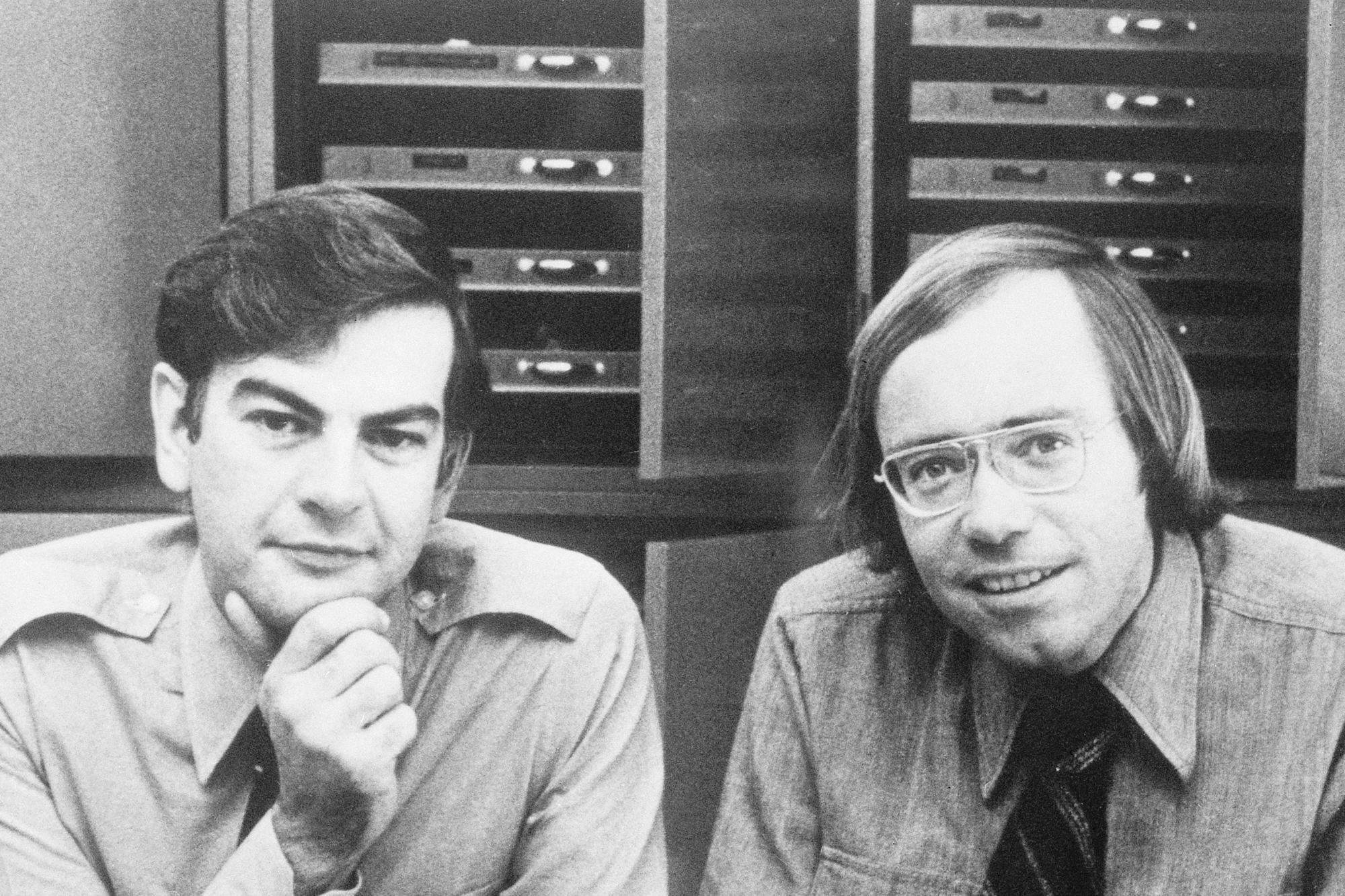 Two men pose in front of a case of specimen drawers.